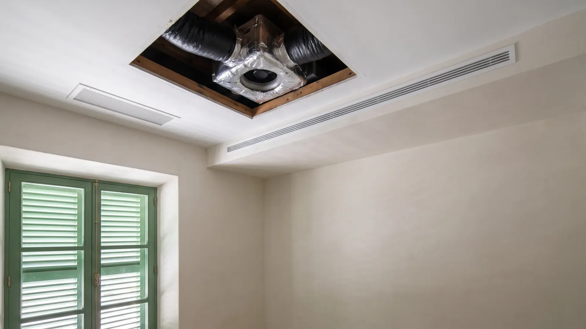 Insulated flexible duct and a fan seen through an open ceiling hatch, a slot diffuser set into the bulkhead below