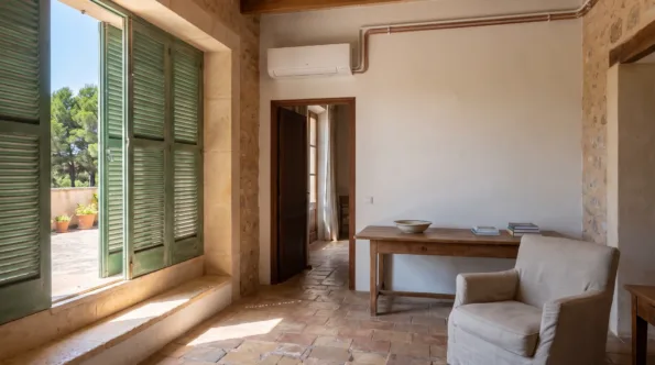A wall unit in a room with a timber table and armchair, shutters folded back onto a terrace