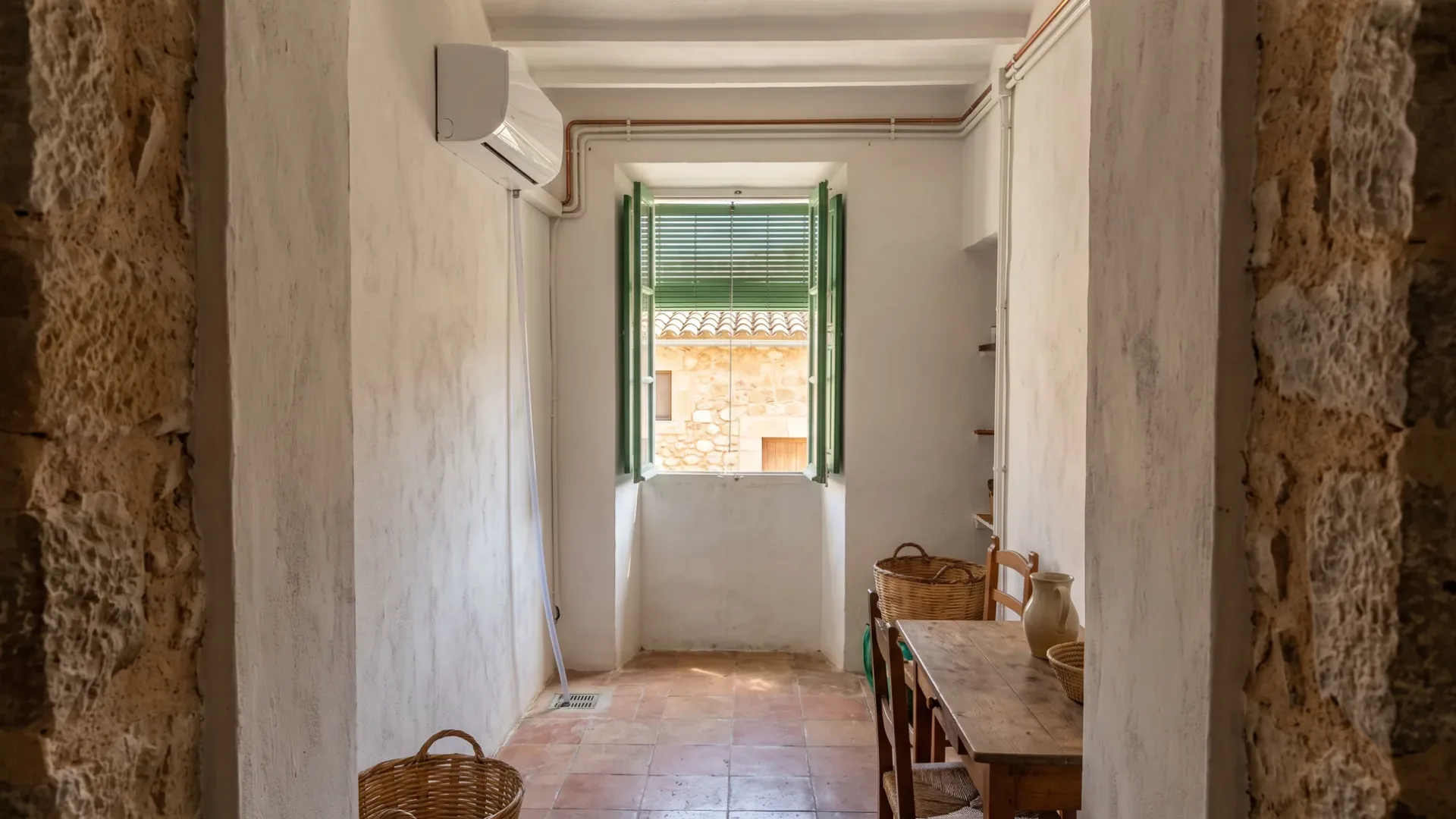 A wall unit in a narrow passage between thick stone walls, a shuttered window at the far end