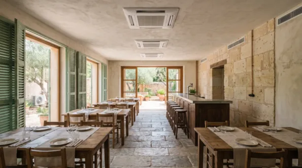 Three ceiling cassettes in a row above laid tables and a bar, shutters standing open to a terrace beyond